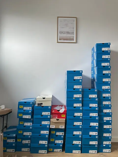 Rows of blue Adidas boxes stacked along a wall