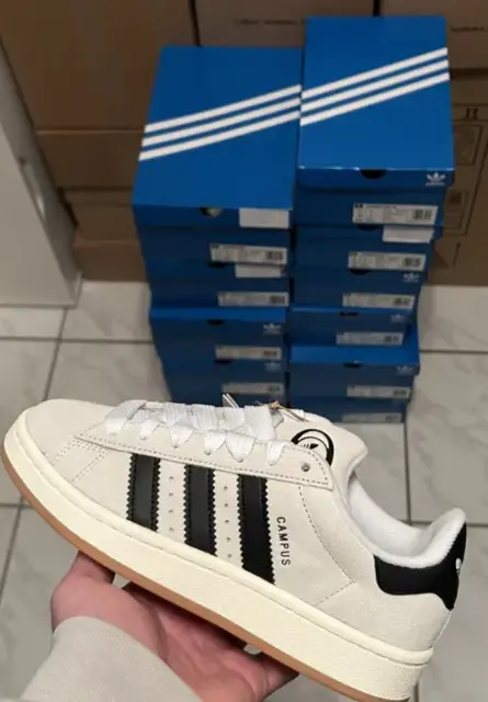 Adidas Campus in hand, a stack of boxes behind it