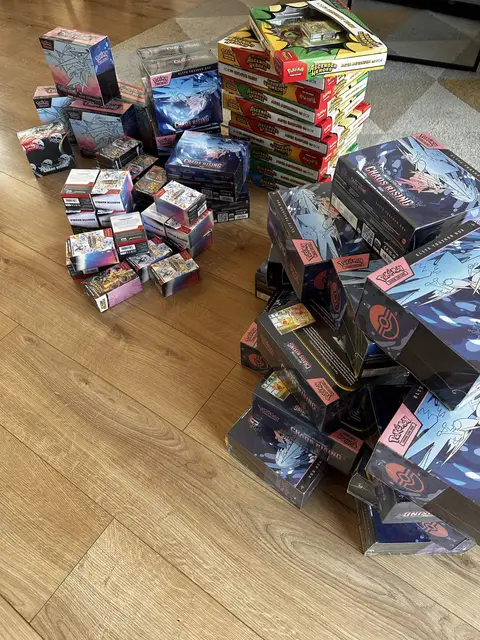 Pokémon TCG boxes piled across a living-room floor